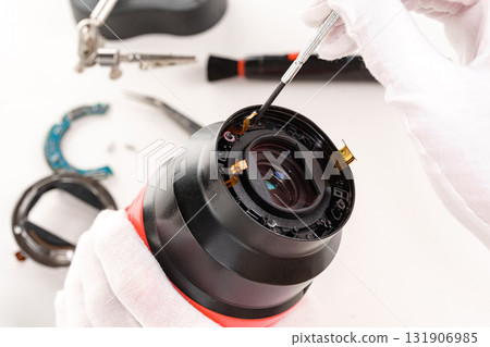 the hands of the master with gloves and a broken lens of a professional camera. 131906985