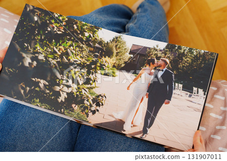 Female hands flipping through a photo book with wedding photos Female hands flipping through a photo book with wedding photos 131907011