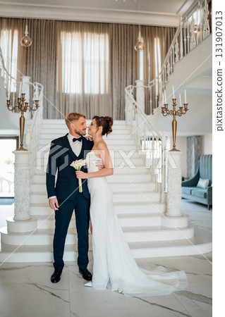 Beautiful and happy bride and groom on a large beautiful staircase. Beautiful and happy bride and groom on a large beautiful staircase. 131907013