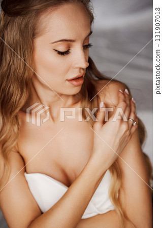 Sensual portrait of a sexy blonde young woman in a white off-the-shoulder dress. 131907018