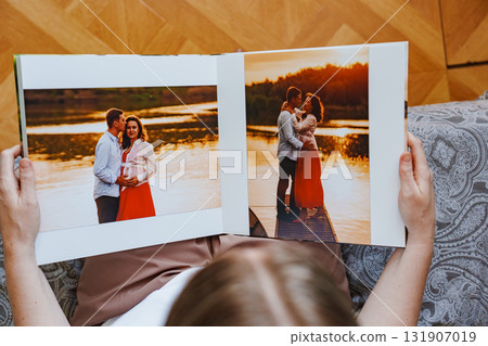 woman is holding and flipping through a photo book with a pregnancy photo shoot woman is holding and flipping through a photo book with a pregnancy photo shoot 131907019