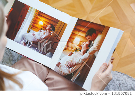 woman is holding and flipping through a photo book with a pregnancy photo shoot 131907091
