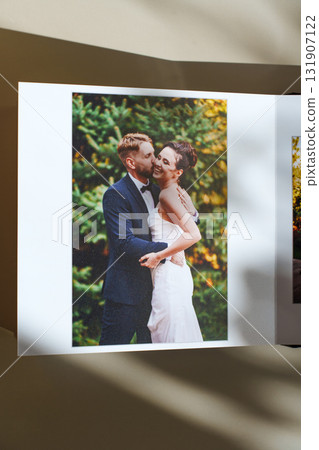 page of an open photo book with wedding photos on a white table 131907122