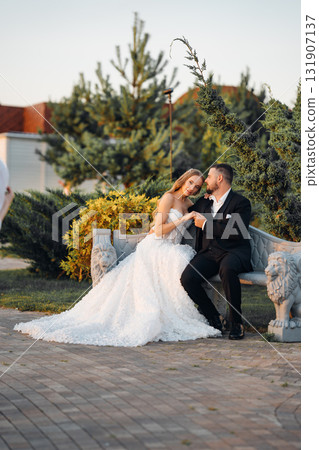 Gentle and happy bride and groom at sunset in the park on a bench. Gentle and happy bride and groom at sunset in the park on a bench. 131907137