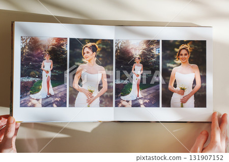 Female hands flipping through a photo book with wedding photos on a white table Female hands flipping through a photo book with wedding photos on a white table 131907152