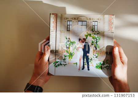 hands with a photo book with wedding photos on a white table hands with a photo book with wedding photos on a white table 131907153