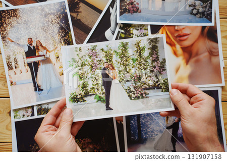 Men's hands put on the table and show wedding photos. Men's hands put on the table and show wedding photos. 131907158