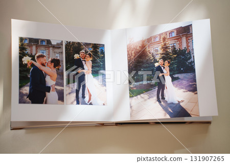 an open photo book with wedding photos on a white table 131907265