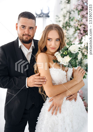 Beautiful and gentle bride and groom on the background of flowers in the decor. Beautiful and gentle bride and groom on the background of flowers in the decor. 131907283