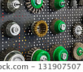 Collection of various wire brushes and tools arranged on a textured display board in a workshop setting 131907507