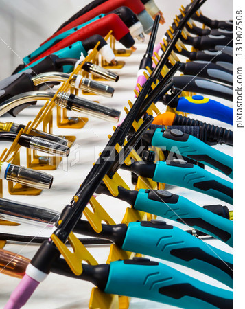 Various types of welding torches and tools displayed on a rack in a workshop setting Various types of welding torches and tools displayed on a rack in a workshop setting 131907508