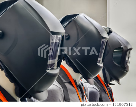 Workers in protective helmets prepare for a safety demonstration in an industrial setting during daylight hours Workers in protective helmets prepare for a safety demonstration in an industrial setting during daylight hours 131907512