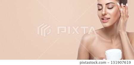 Beauty Woman Concept. Skin care. Portrait of female model holding and applying cosmetic moisturizing cream and touch own face. Nude make-up. Skin Protection.Panorama, baner With Copy Space. Beauty Woman Concept. Skin care. Portrait of female model holding and applying cosmetic moisturizing cream and touch own face. Nude make-up. Skin Protection.Panorama, baner With Copy Space. 131907619