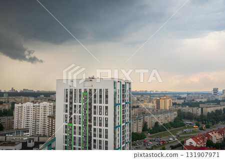 Ominous storm clouds above city skyline as rain starts to fall. Residential and commercial buildings stretch across urban area 131907971