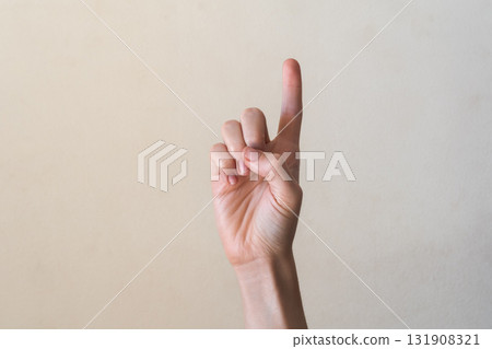 A hand with a light skin tone is raised, showing the number one with the index finger extended. The background is a neutral color, emphasizing the gesture. 131908321