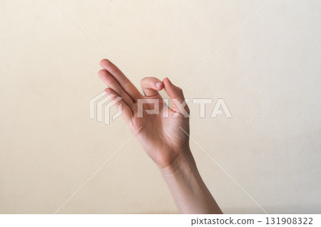 A close-up of a human hand making an 'OK' gesture against a neutral background. Gyan mudra. The hand is of a young adult with light skin and slender fingers. A close-up of a human hand making an 'OK' gesture against a neutral background. Gyan mudra. The hand is of a young adult with light skin and slender fingers. 131908322