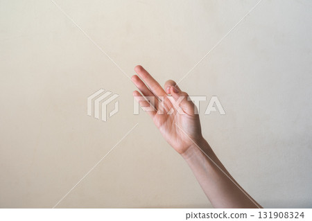 A close-up of a human hand making an 'OK' gesture against a neutral background. Gyan mudra. The hand is of a young adult with light skin and slender fingers. 131908324