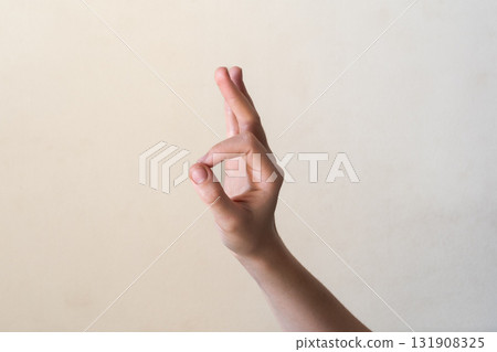A close-up of a human hand making an 'OK' gesture against a neutral background. Gyan mudra. The hand is of a young adult with light skin and slender fingers. 131908325
