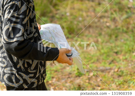 Orienteering athlete running through a summer forest with a map and compass. 131908359