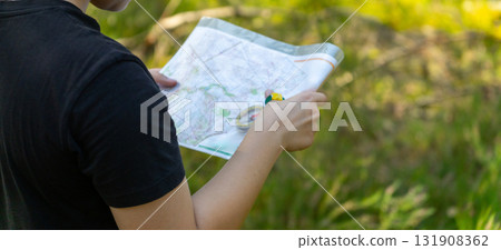 Orienteering athlete running through a summer forest with a map and compass. 131908362