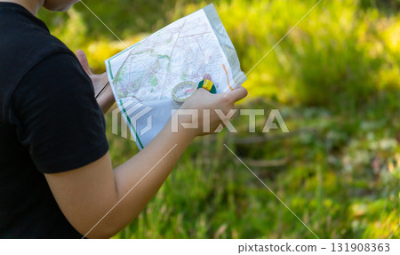 Orienteering athlete running through a summer forest with a map and compass. Orienteering athlete running through a summer forest with a map and compass. 131908363