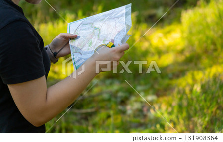 Orienteering athlete running through a summer forest with a map and compass. 131908364