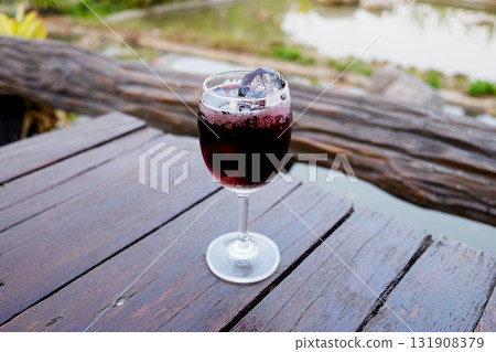 Chilled red wine spritzer with Ice cube in glass on wooden table outdoor in garden Chilled red wine spritzer with Ice cube in glass on wooden table outdoor in garden 131908379