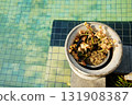 Top view of  yellow flowers are withering in a white clay pot with swimming pool 131908387