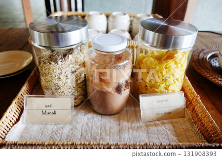 Various uncooked cereals with muesli and corn flake in glass jar on table 131908393