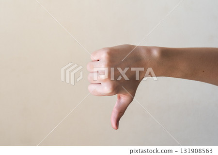A close-up of a human hand giving a thumbs-down gesture against a plain background. The hand is Caucasian with visible veins and a well-groomed appearance. A close-up of a human hand giving a thumbs-down gesture against a plain background. The hand is Caucasian with visible veins and a well-groomed appearance. 131908563