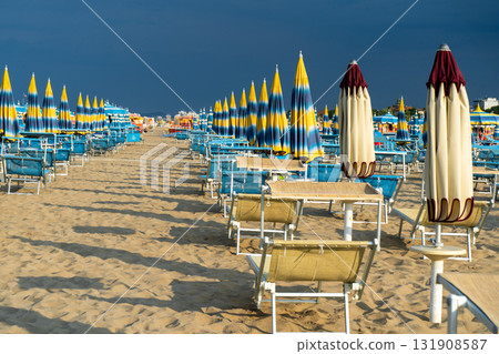 Sun loungers on sandy beach with Umbrellas. Empty seaside resort. Italy. 131908587