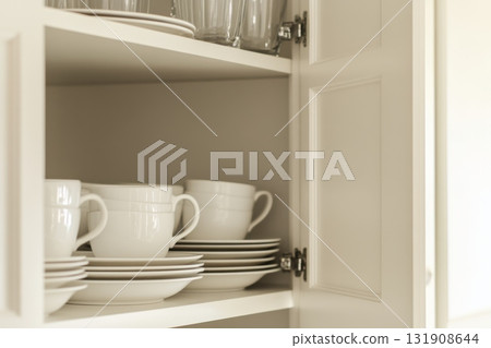 Kitchen cabinet with neatly stacked different dishware, utensils. White plates stack. Modern kitchen shelf. Shelves with ceramic bowls, cups, glasses. Open cupboard shelving plate dishes. Clean home 131908644
