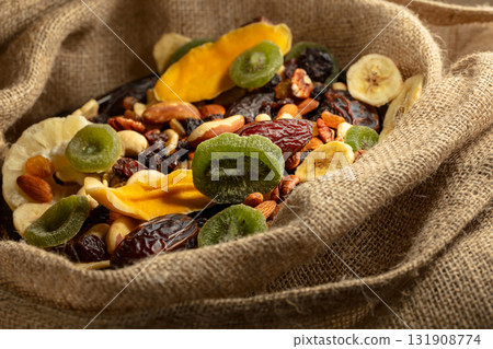 Dried tropical fruits and nuts in burlap bag. 131908774