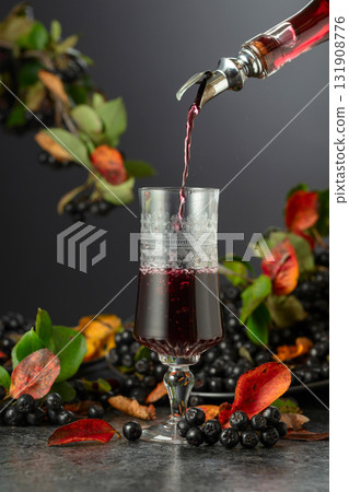 Black chokeberry drink and fresh berries on a black stone table. Black chokeberry drink and fresh berries on a black stone table. 131908776