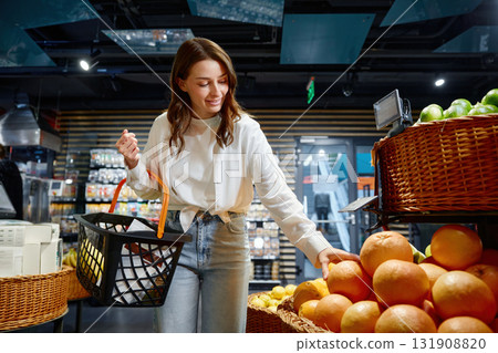 A woman is shopping for oranges in a grocery store A woman is shopping for oranges in a grocery store 131908820