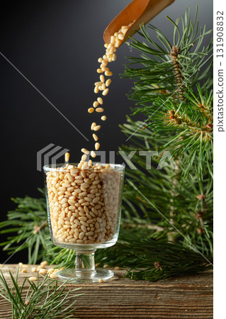 Pine nuts is poured in a glass bowl. 131908832