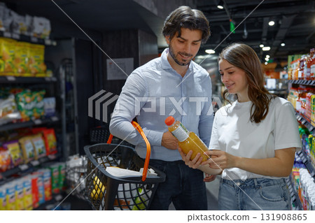 A man and woman are examining a bottle of orange juice A man and woman are examining a bottle of orange juice 131908865