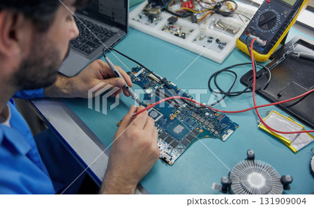 Technician man worker is focused on working with a motherboard 131909004