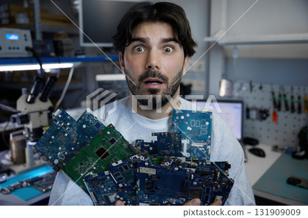Surprised man holds a bunch of electronic components Surprised man holds a bunch of electronic components 131909009