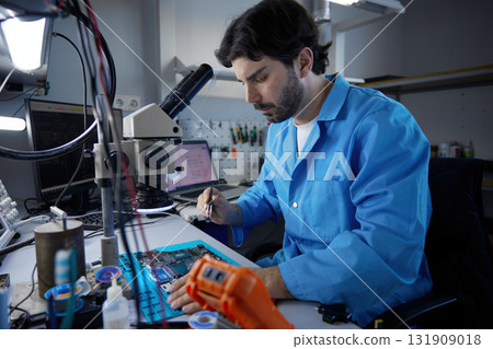 A technician works on a complex circuit board with precision tools and techniques A technician works on a complex circuit board with precision tools and techniques 131909018