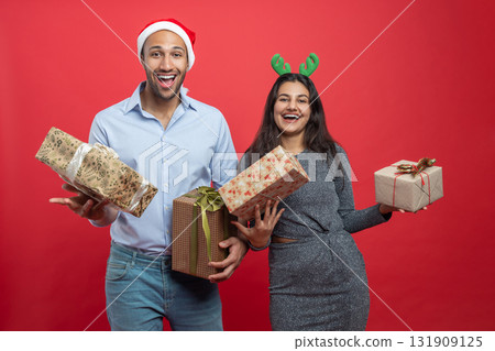 Family holding present boxes and holiday decorations celebrating Xmas eve wearing festive hats 131909125