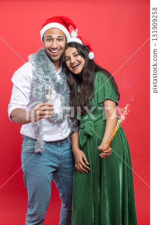 Happy couple in Santa hats with champagne glasses and holding sparkle celebrating Xmas together 131909258