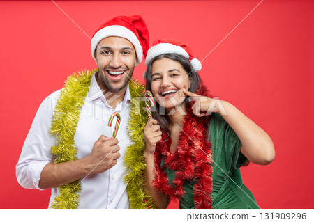 Cheerful family wearing Santa hats celebrating Xmas together with decorations and candy canes Cheerful family wearing Santa hats celebrating Xmas together with decorations and candy canes 131909296