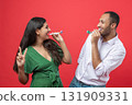Happy couple celebrating holiday on party blowing in whistle isolated over red background 131909331