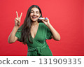 Festive beautiful woman winking showing v-sign and holding colorful tube while celebrating 131909335