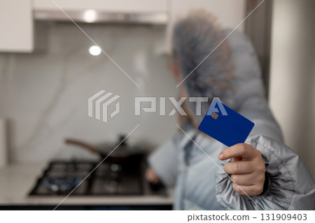 Paying Heating Bill in Winter. Woman With Credit Card in Warm Jacket Indoors 131909403