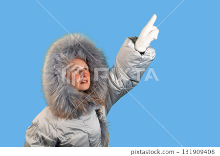 Woman in Winter Coat Pointing Upward Toward Copy Space Woman in Winter Coat Pointing Upward Toward Copy Space 131909408