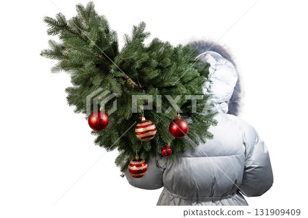 Girl Carries Christmas Tree With Ornaments on Her Back in Winter 131909409