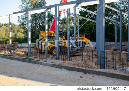 Telescopic handlers and a mobile crane at a construction site in the evening in the rays Telescopic handlers and a mobile crane at a construction site in the evening in the rays 131909447