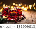 Glasses of mulled wine with cinnamon stick, orange slice, anise. Traditional Red Christmas drink with citrus fruits, berries on warm holiday background. Wine with spices on a festive table. Copy space 131909613